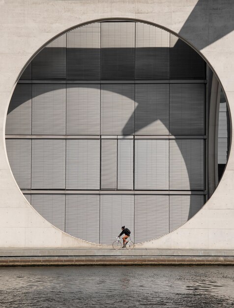 Woman riding bicycle by river against built structure