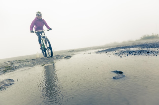 Photo woman riding bicycle on wet road against sky