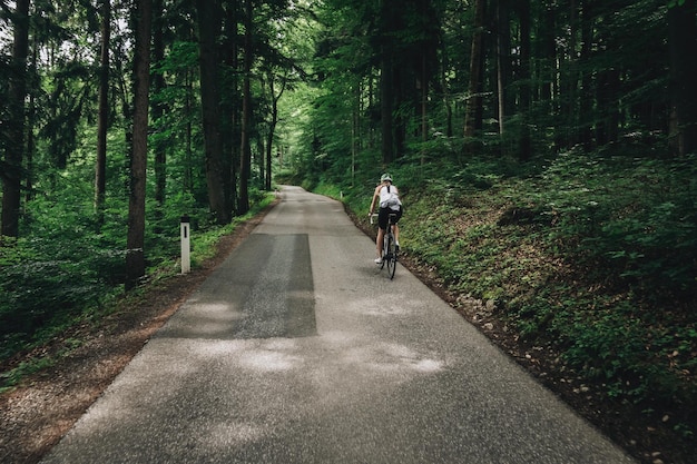 Женщина едет на велосипеде по дороге в лесу в австрийских Альпах