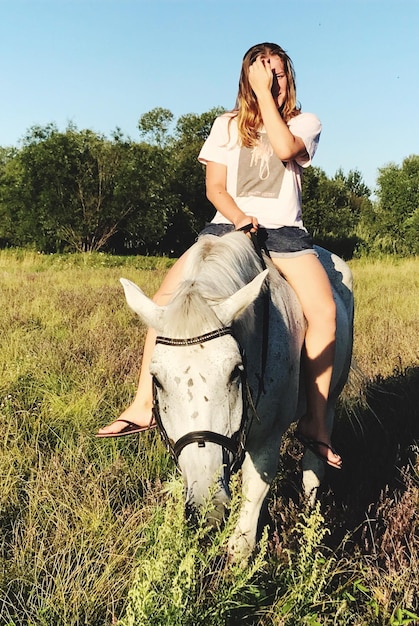 Foto donna a cavallo sul campo contro gli alberi