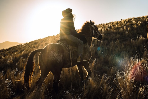 Photo woman riding horse on field during sunset