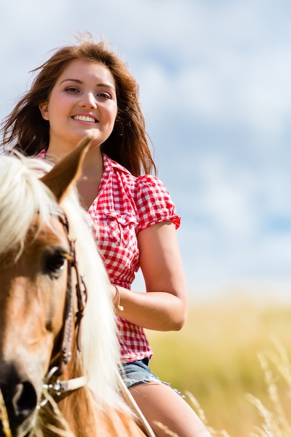 La donna a cavallo nel prato estivo