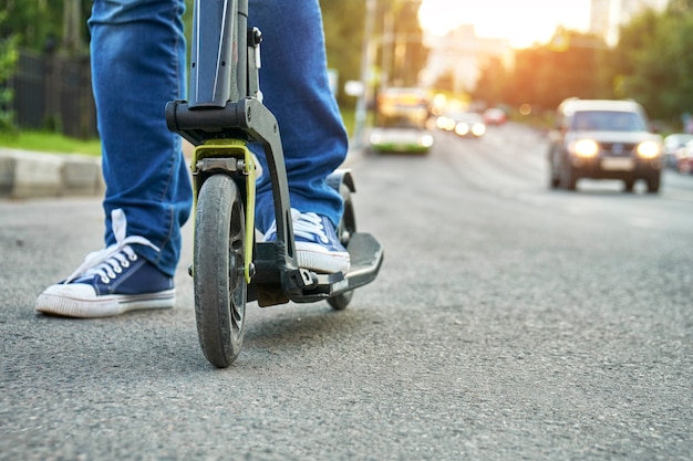 Woman riding on kick scooter along busy street in the city