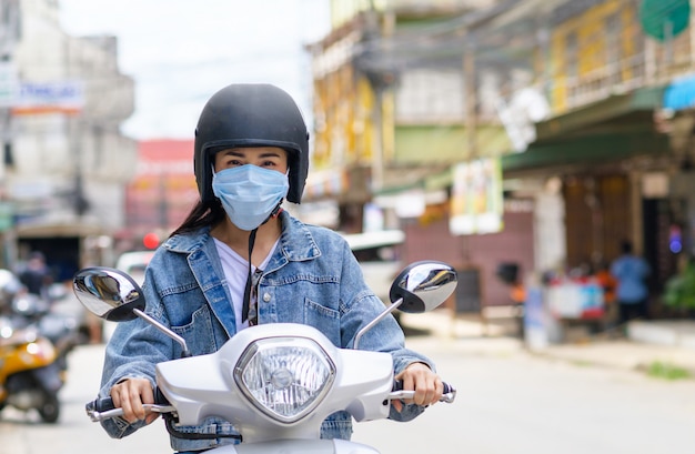 Woman riding a motorcycle wearing a mask in the city.