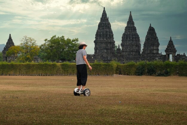 Woman riding a self balancing electric hover board in Prambanan Temple national park grass field