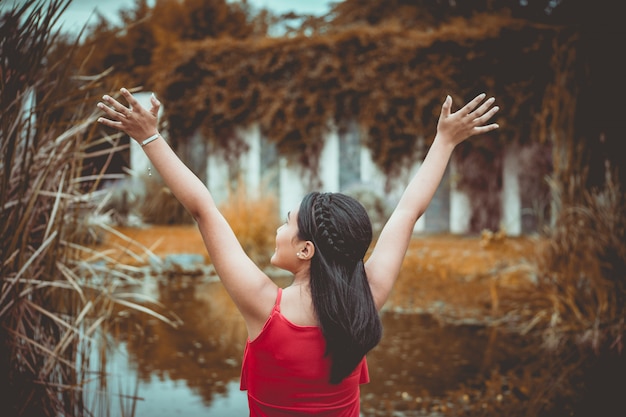 Photo woman rising her hands in front of a lake