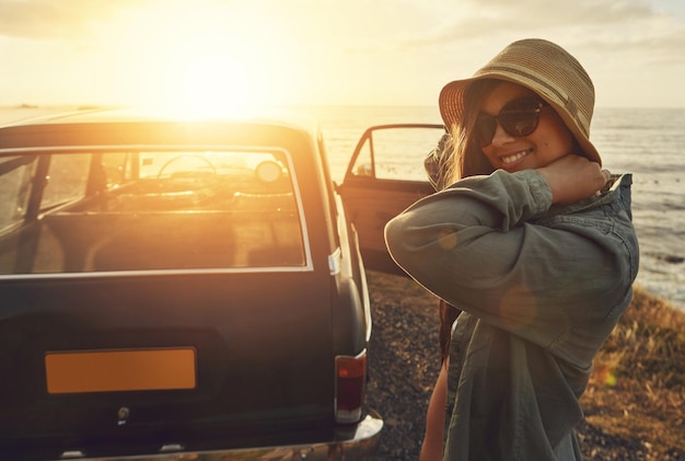 Woman road trip and smile for sunset travel vacation or journey with a view of the ocean in outdoor nature Happy female traveler smiling in happiness for summer with lens flare for a beach drive