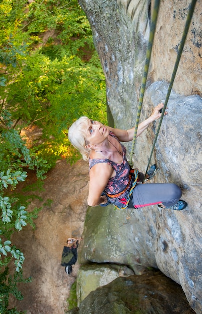 Woman rock climber is climbing on a rocky wall