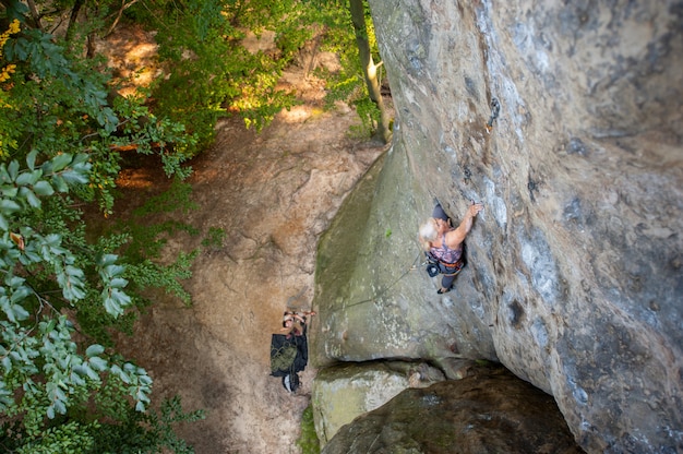 女性ロック・クライマーは岩が多い壁に登っています