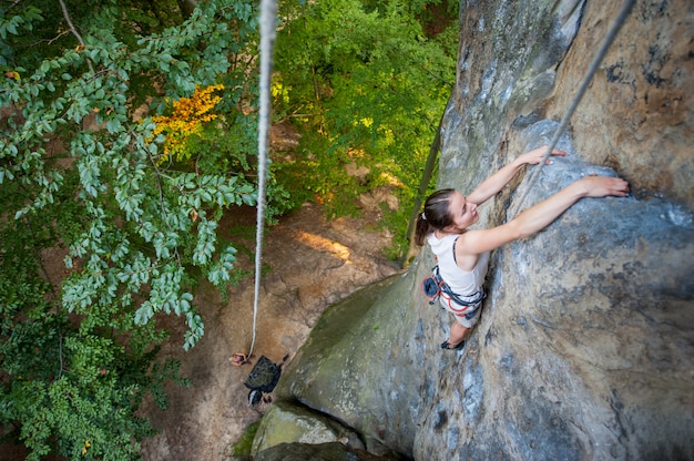 Woman rock climber is climbing on a rocky wall