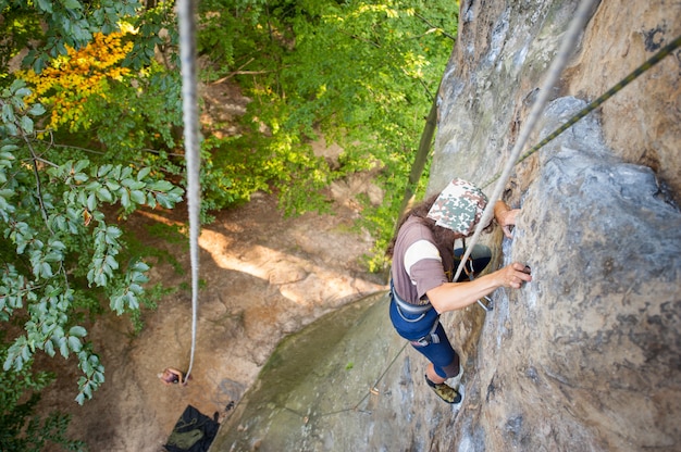 Woman rock climber is climbing on a rocky wall