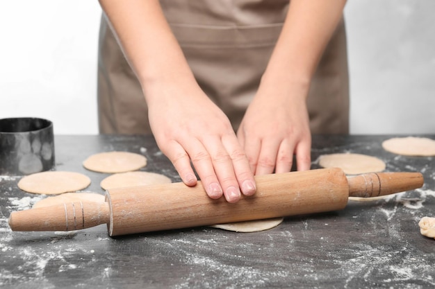 Woman rolling dough on table closeup Cooking dumplings