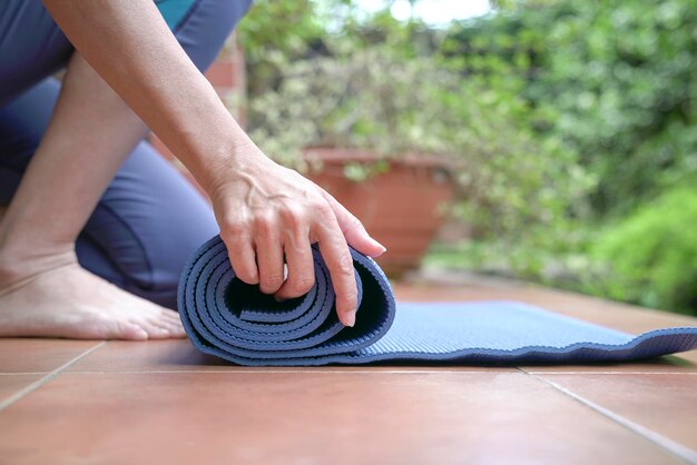 Donna che stende il tappetino per esercizi concetto di stile di vita sano