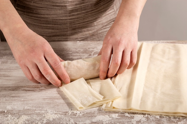 Woman rolling up phyllo pasta filled with tuna to cook a recipe