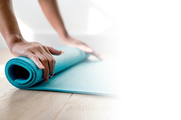 Woman rolling up a yoga mat during coronavirus quarantine