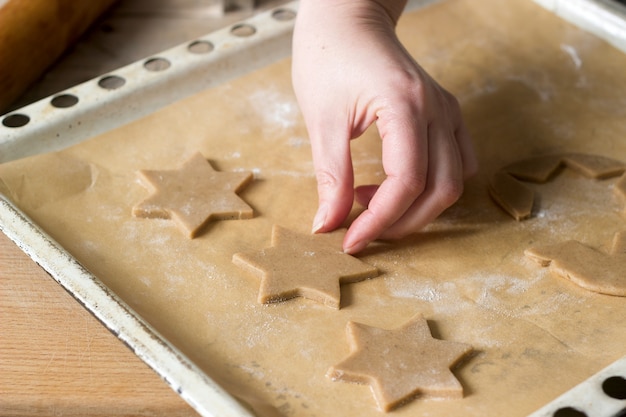 A woman rolls out the dough and cuts out the biscuits.