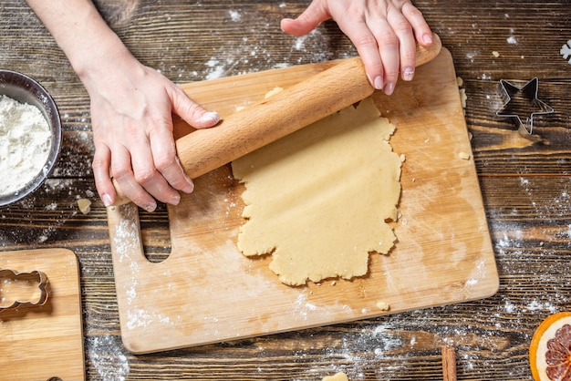 Woman rolls out the dough with a rolling pin and shapes