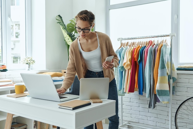a woman in a room with a laptop and a colorful clothes hanging on the wall