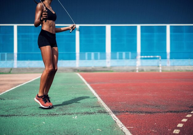 Foto donna che salta la corda su un campo sportivo