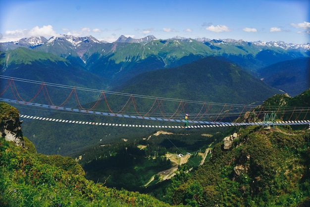 женщина гуляет по веревочному подвесному мосту в горах Кавказа Россия Фото высокого качества