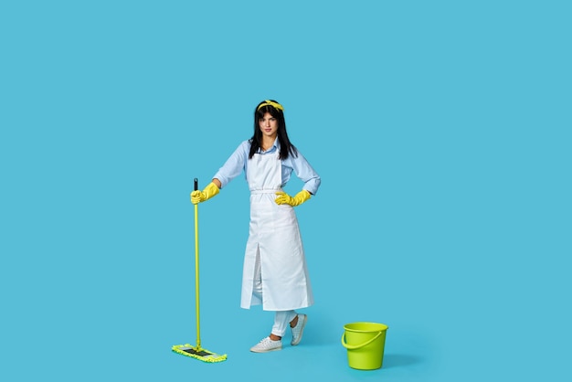 Woman in rubber gloves and cleaner apron with cleaning supplies