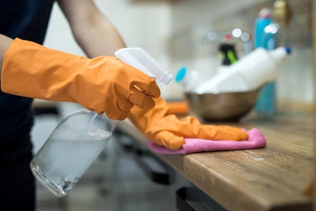 Woman in rubber gloves and cleaning the kitchen counter with sponge. housework