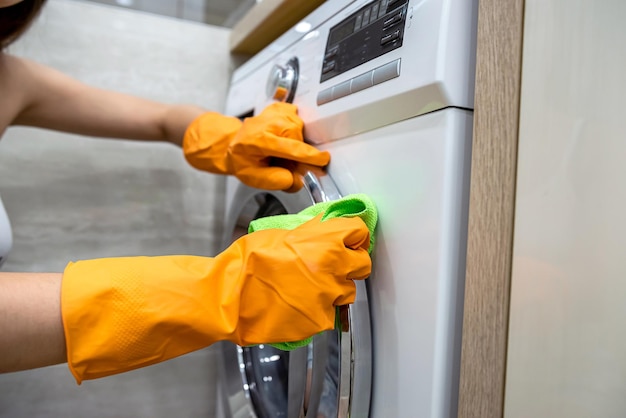 Woman in rubber gloves cleaning washing machine. Cleaning service .