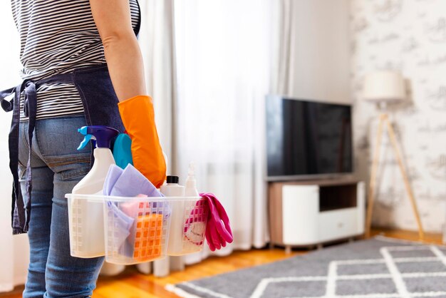 Woman in rubber gloves with basket of cleaning supplies ready to clean up