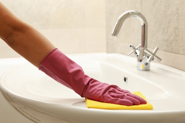 Woman in rubber pink glove cleaning sink