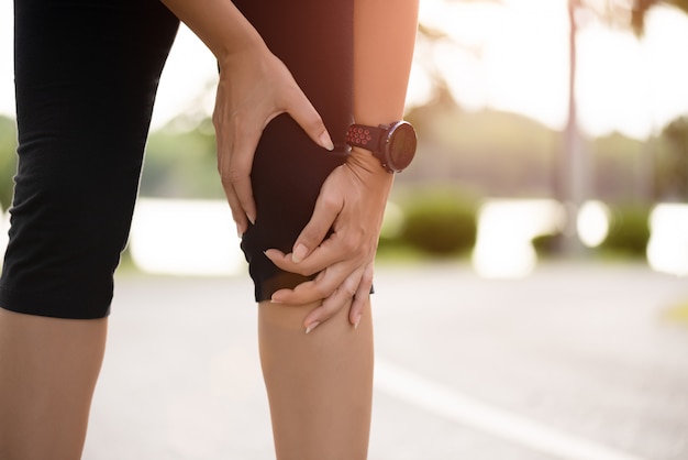 女性ランナーは公園で膝に痛みを感じます。