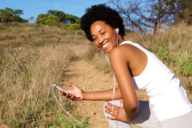 Woman runner outside in field with mobile phone