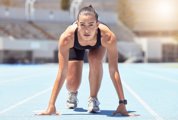 Posizione di partenza del corridore donna su pista competizione o cardio per un allenamento sano e fitness nello stadio focus giovane atleta sportiva femminile pronta a correre sfida velocità e maratona