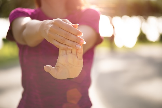 Woman runner stretching hand before run in the park. Outdoor exercise.