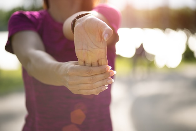 Photo woman runner stretching hand before run in the park.