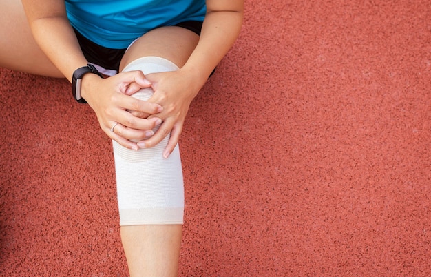 Foto corridore donna che soffre di dolore al ginocchio durante la corsa e l'allenamento all'aperto
