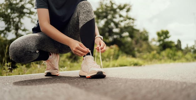 Woman runner tying shoelaces on road