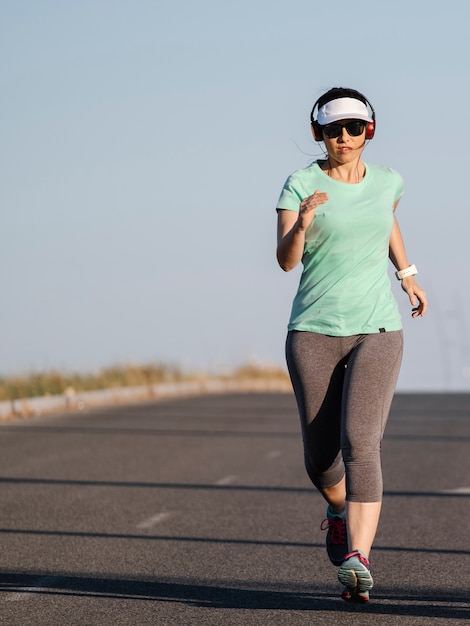 Woman running along the road listening to music