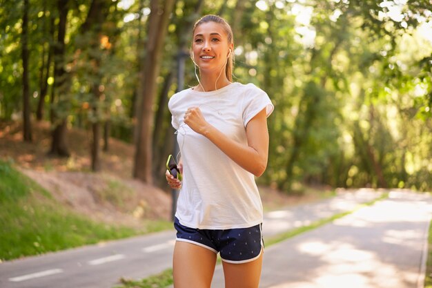 Donna in esecuzione strada asfaltata parco estivo allenamento mattutino femminile caucasico sportivo attivo concetto di stile di vita sano