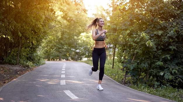 Woman running asphalt road summer park