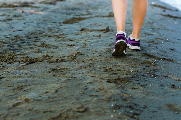 Donna che funziona sulla spiaggia, primo piano delle gambe della donna.