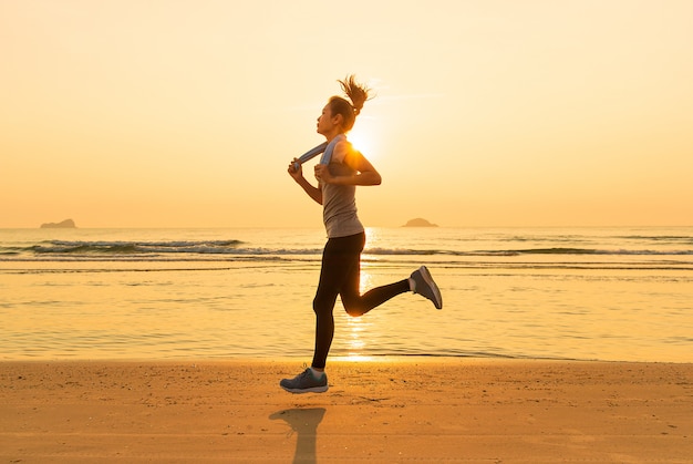 Woman running on beach at sunrise