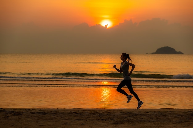 Donna che funziona sulla spiaggia all'alba