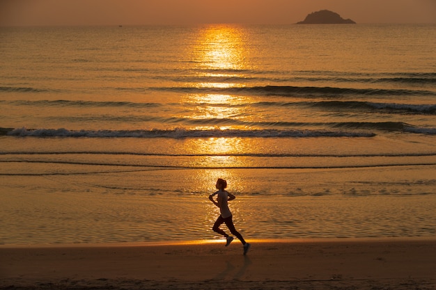 Donna che funziona sulla spiaggia all'alba