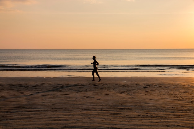 Woman running on the beach at sunset, healthy lifestyle