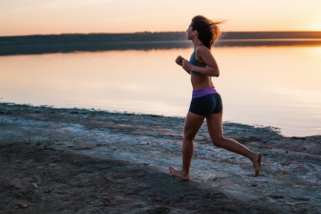 Photo woman running on the beach at sunset.