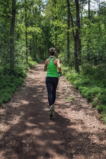 Photo woman running on dirt road in forest