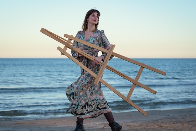 Woman Running Down a Beach Carrying a Easel