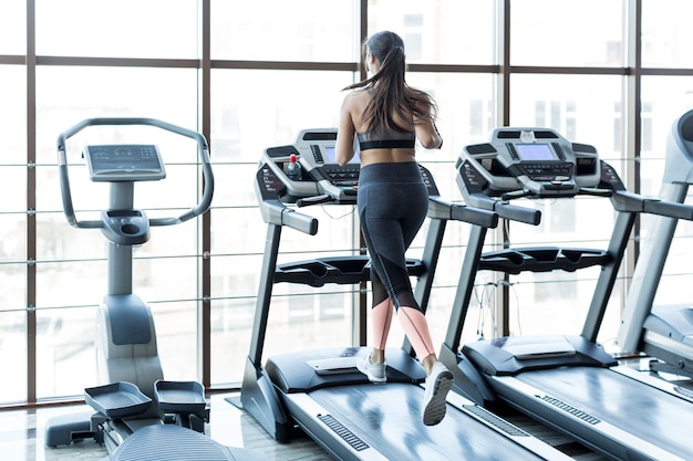 Woman running on race track in sports club