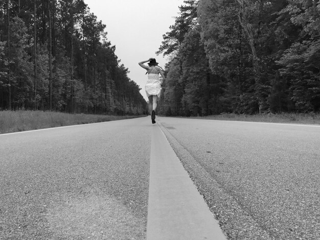 Photo woman running on road against trees