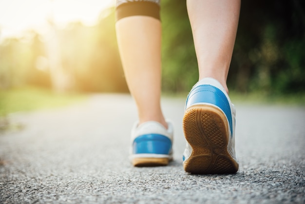 Woman in running shoes stepping on road.